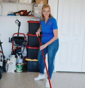 Cheryl with a broom completing a garage organization project in Bloomington
