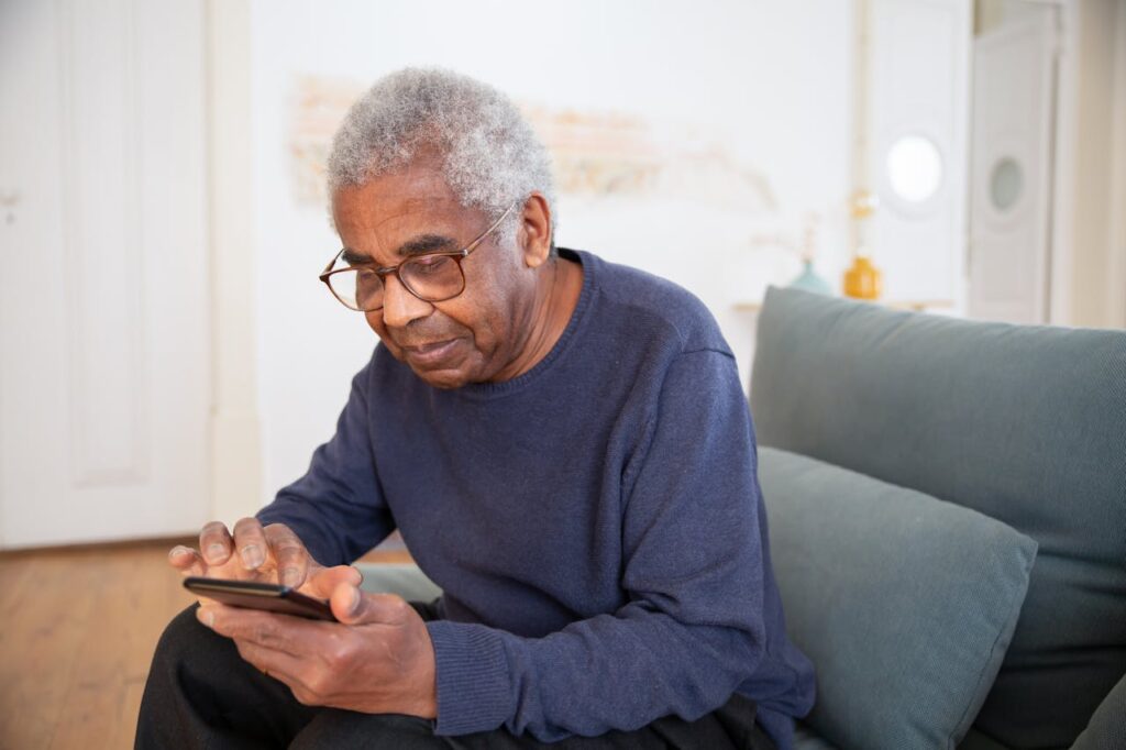 An elderly man is looking at his smart phone